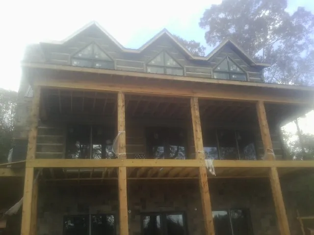 Dormers and porch framing on a large log home under construction — Roof Coating work by our crew in Camp Douglas