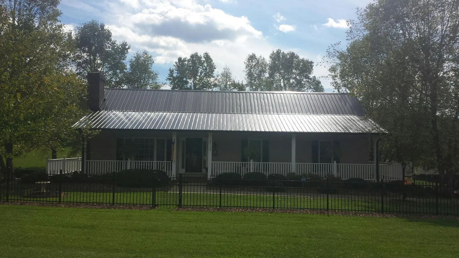 Gray metal roof on a brick ranch with a full width front porch — Gutter Guard Installation work by our crew in Camp Douglas