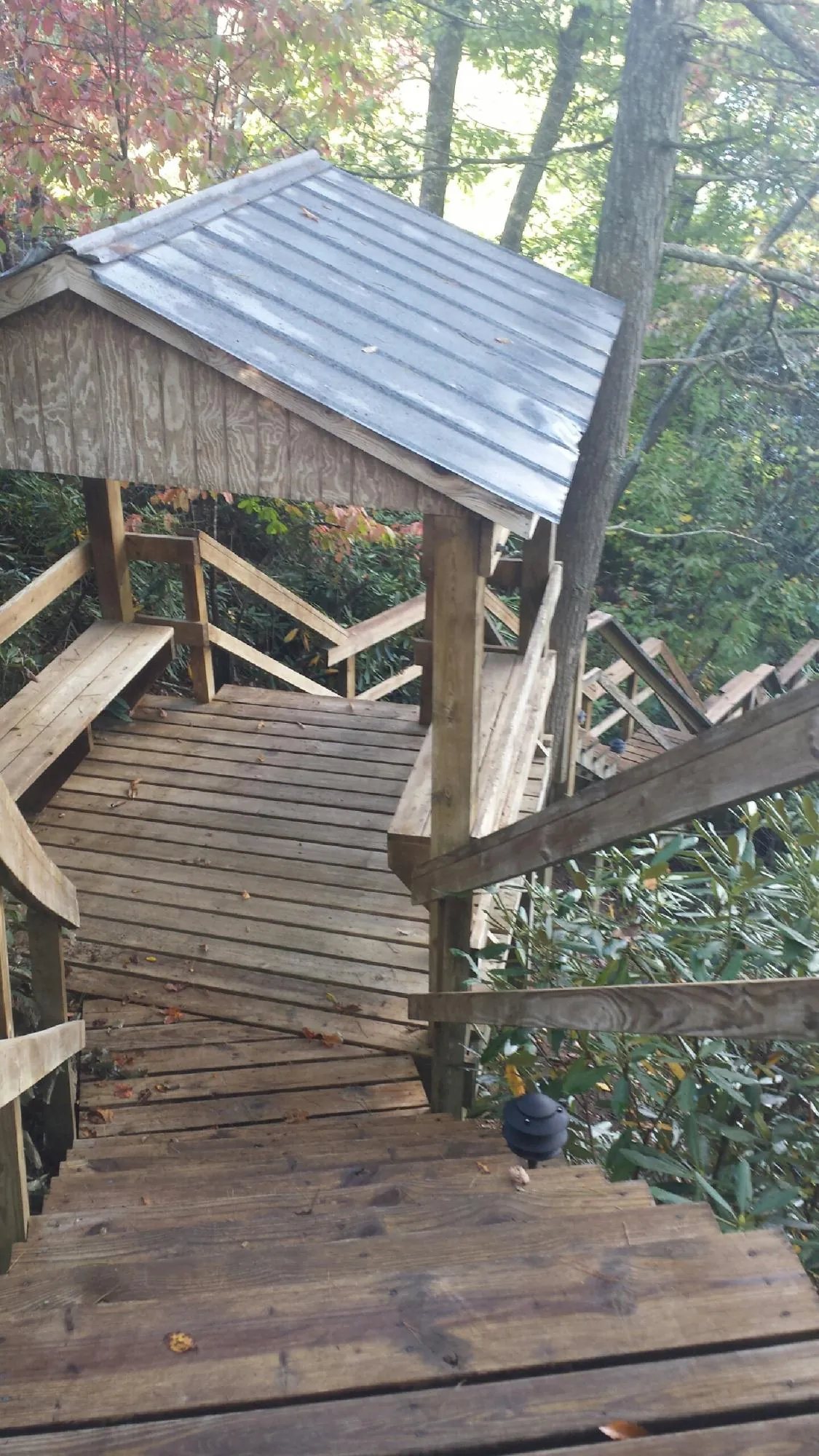Metal roofed shelter over wooden steps on a wooded walkway — Skylight Repair & Installation work by our crew in Camp Douglas