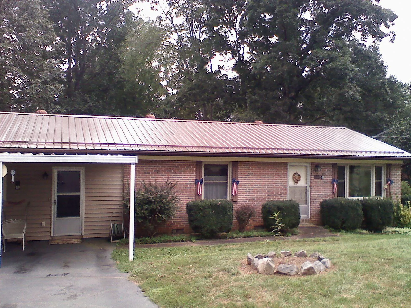 Bronze metal roof and carport on a brick ranch home — Roof Repair work by our crew in Camp Douglas